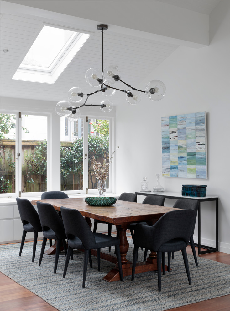 Example of a transitional medium tone wood floor dining room design in Sydney with white walls