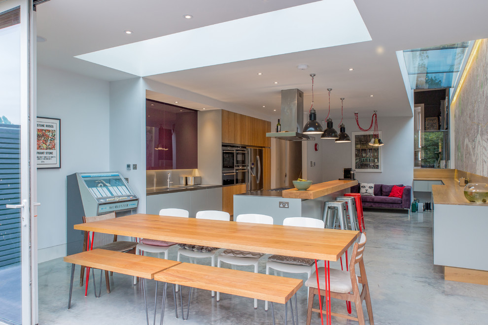 Immagine di una sala da pranzo aperta verso la cucina design di medie dimensioni con pareti bianche, pavimento in cemento e nessun camino
