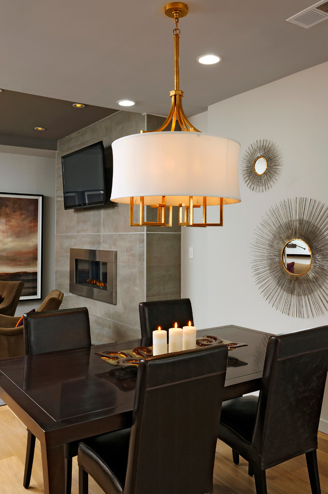 Cette image montre une petite salle à manger ouverte sur le salon design avec un mur gris, parquet clair, une cheminée standard et un manteau de cheminée en pierre.
