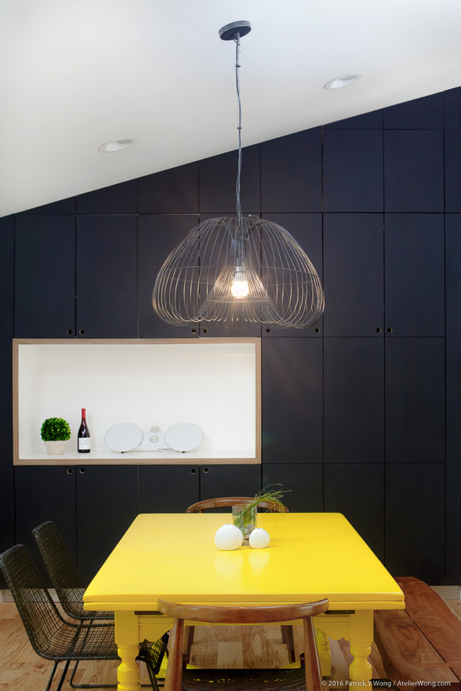 Immagine di una sala da pranzo aperta verso la cucina minimal con pareti nere e parquet chiaro