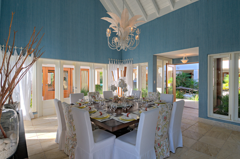 Foto di una sala da pranzo aperta verso il soggiorno tropicale di medie dimensioni con pareti blu e pavimento in travertino