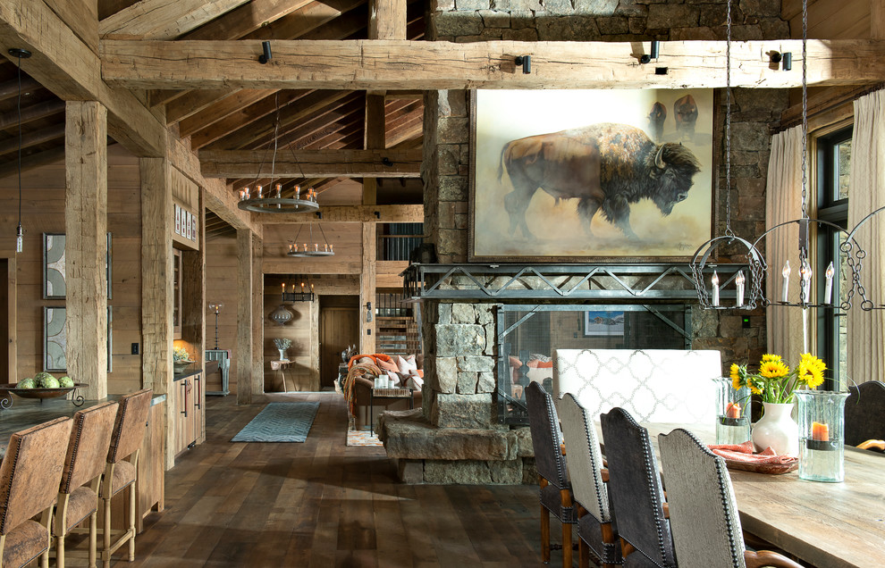 Inspiration for an expansive rustic kitchen/dining room in Other with brown walls, medium hardwood flooring, a two-sided fireplace, a stone fireplace surround and brown floors.