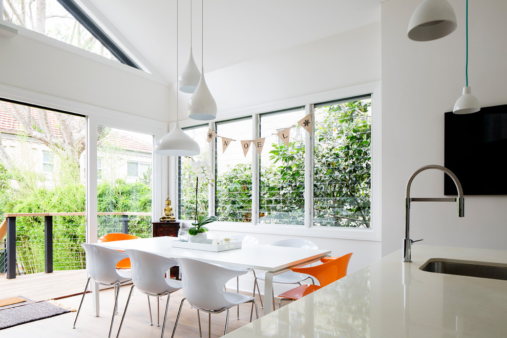 Esempio di una sala da pranzo aperta verso la cucina contemporanea con pareti bianche, pavimento in legno massello medio e pavimento marrone