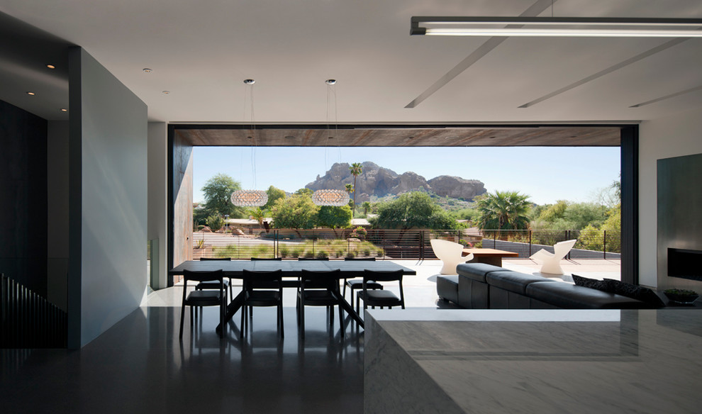 На фото: гостиная-столовая среднего размера в стиле модернизм с белыми стенами, бетонным полом, стандартным камином и фасадом камина из металла