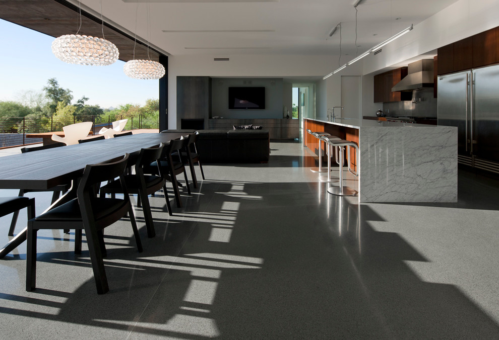 Immagine di una sala da pranzo aperta verso il soggiorno minimalista di medie dimensioni con pareti bianche e pavimento in cemento