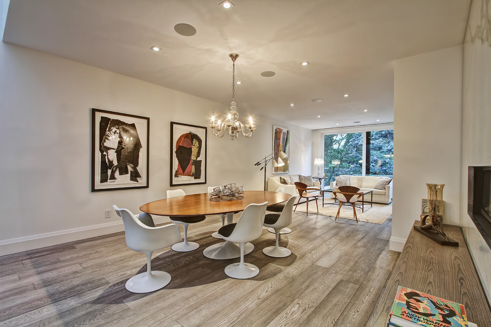 Idée de décoration pour une salle à manger ouverte sur le salon design avec un mur blanc, un sol en bois brun et une cheminée standard.