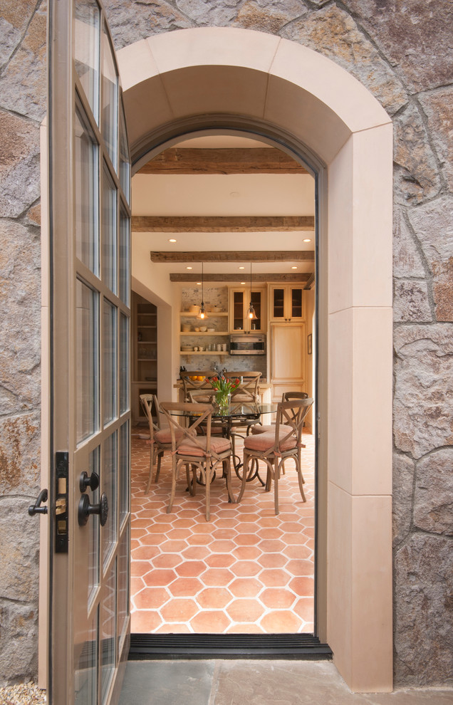 Inspiration pour une salle à manger ouverte sur la cuisine traditionnelle avec un mur beige, tomettes au sol, un sol orange et poutres apparentes.