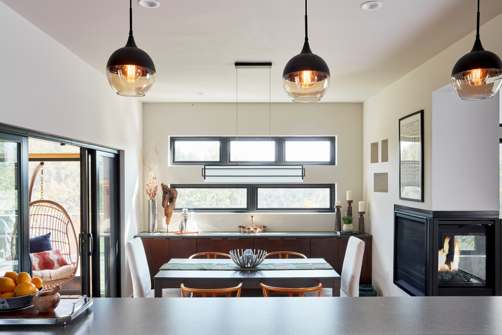 Foto de comedor de cocina moderno pequeño con paredes blancas, suelo de madera en tonos medios, chimenea de doble cara, marco de chimenea de yeso y suelo marrón