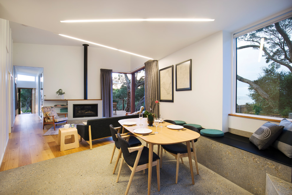 На фото: гостиная-столовая среднего размера в скандинавском стиле с белыми стенами, бетонным полом, печью-буржуйкой, фасадом камина из бетона и серым полом с
