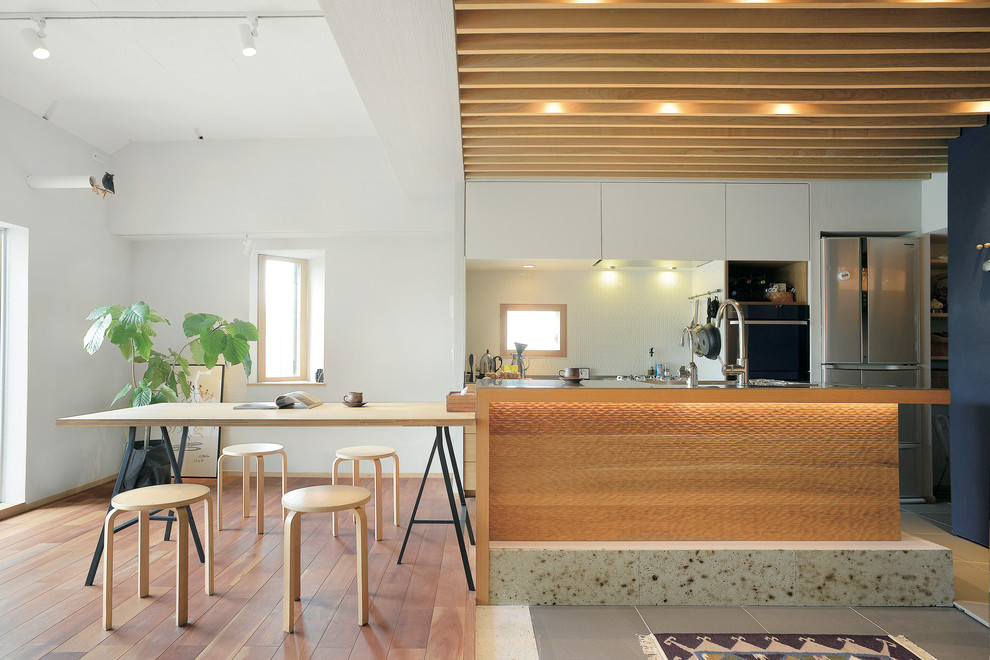 Moderne Wohnküche ohne Kamin mit weißer Wandfarbe und braunem Boden in Sonstige