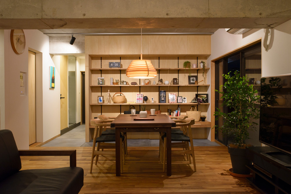 Ispirazione per una sala da pranzo aperta verso il soggiorno etnica con pareti bianche e pavimento in legno massello medio