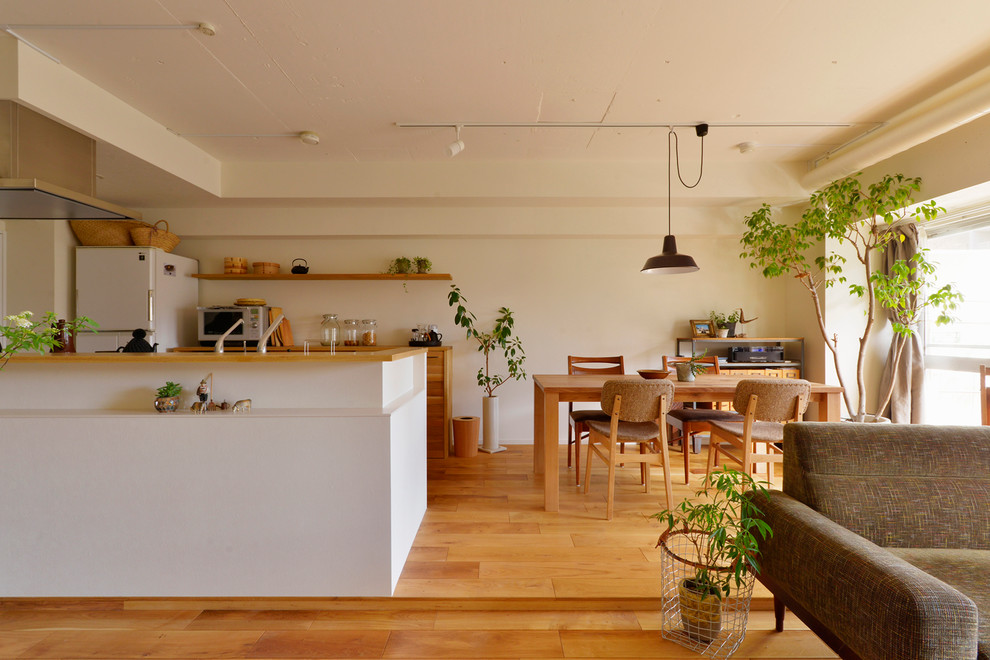 Réalisation d'une salle à manger ouverte sur le salon asiatique avec un mur blanc, un sol en bois brun et un sol marron.