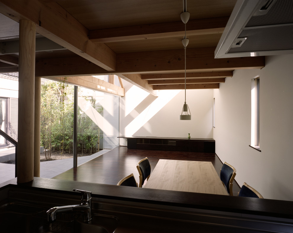 Imagen de comedor de estilo zen pequeño abierto sin chimenea con paredes blancas, suelo de madera oscura y suelo negro