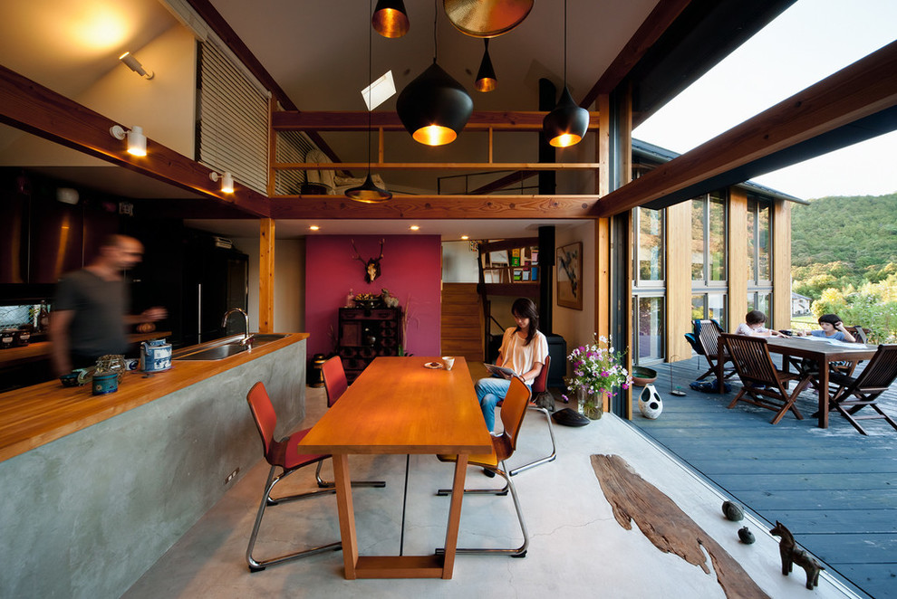 Ispirazione per una sala da pranzo aperta verso il soggiorno eclettica con pavimento in cemento e stufa a legna