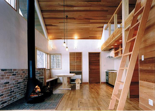 Exemple d'une salle à manger ouverte sur le salon tendance avec un mur blanc, parquet clair, un poêle à bois et un manteau de cheminée en brique.