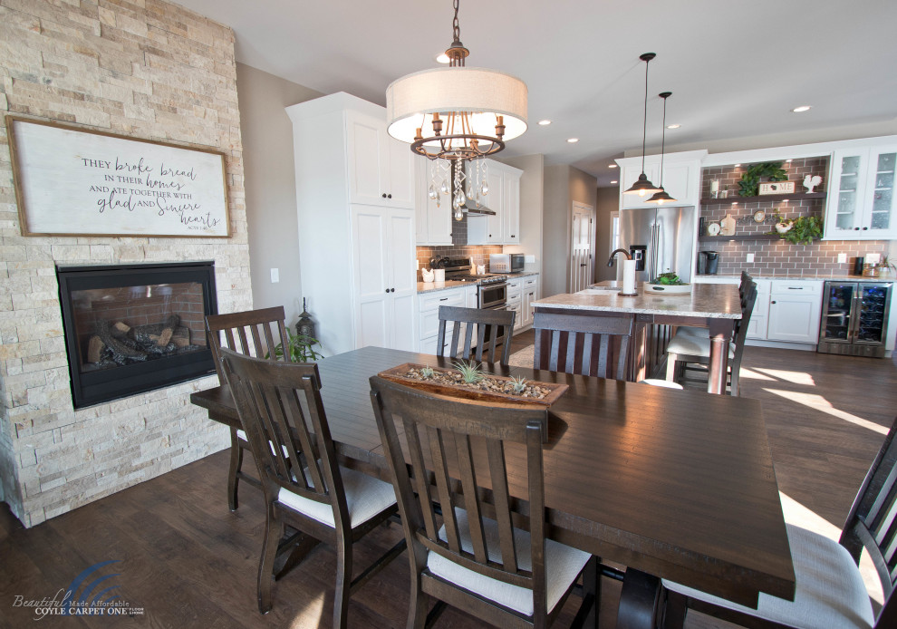 Mittelgroße Wohnküche mit beiger Wandfarbe, Vinylboden, Kamin, Kaminumrandung aus gestapelten Steinen und braunem Boden in Sonstige