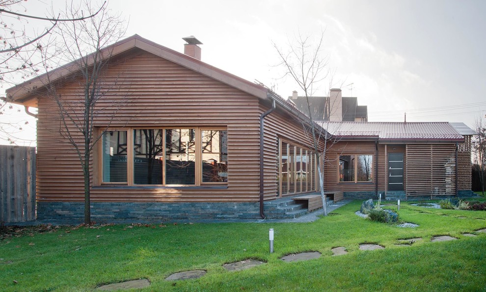 Imagen de fachada de casa beige de estilo de casa de campo de una planta con revestimiento de madera, tejado a dos aguas y tejado de teja de barro