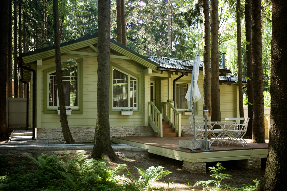 Ejemplo de fachada de casa verde escandinava de tamaño medio de una planta con revestimiento de madera, tejado a dos aguas y tejado de teja de barro