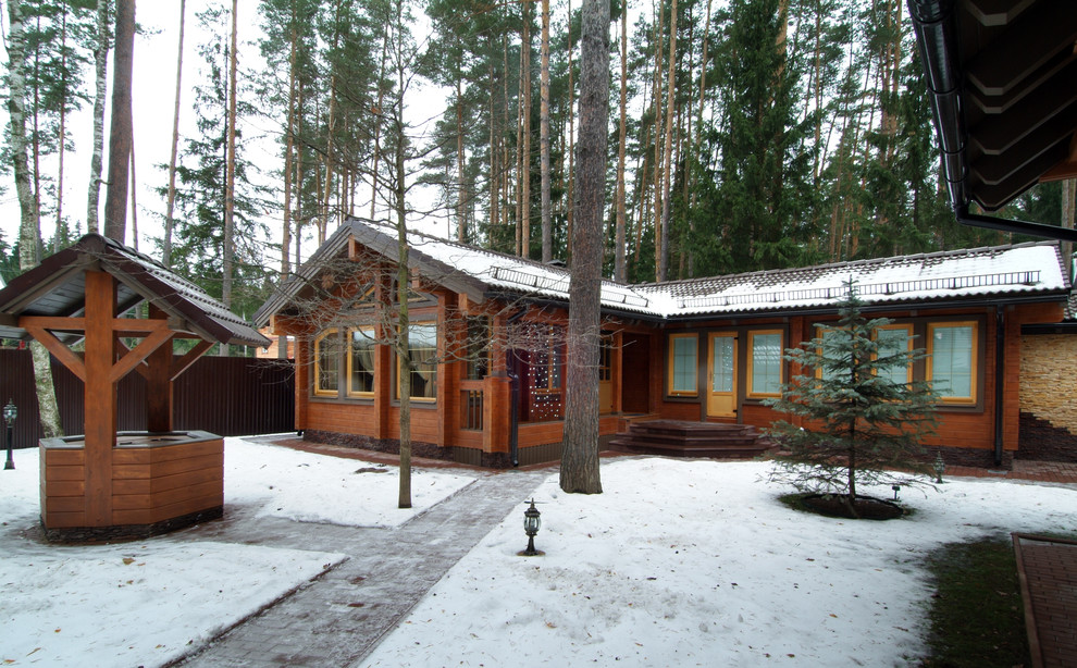 Idée de décoration pour une façade de maison marron en bois de taille moyenne et de plain-pied avec un toit à deux pans et un toit en tuile.