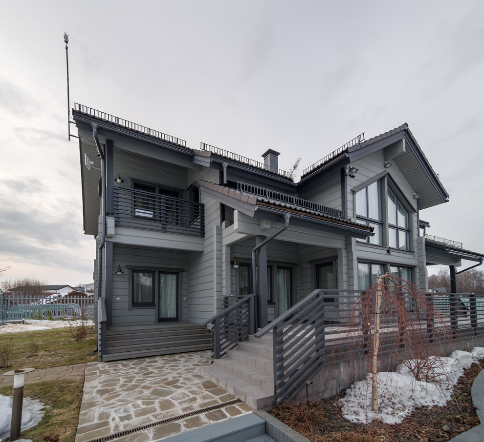Cette photo montre une façade de maison grise chic en bois à un étage avec un toit à deux pans.
