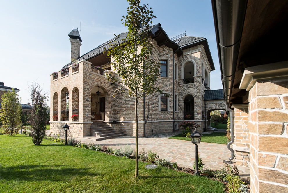 Example of a tuscan beige two-story stone exterior home design in Moscow