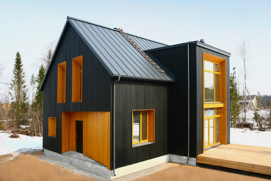 Imagen de fachada negra nórdica de dos plantas con revestimiento de madera y tejado a dos aguas