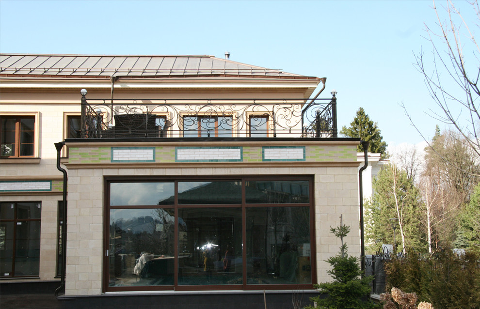 На фото: большой, трехэтажный, бежевый частный загородный дом в стиле неоклассика (современная классика) с комбинированной облицовкой, двускатной крышей и металлической крышей с
