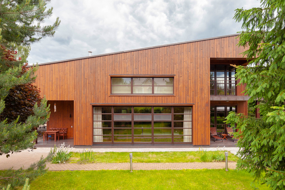 Cette photo montre une façade de maison marron tendance en bois à un étage avec un toit en appentis.