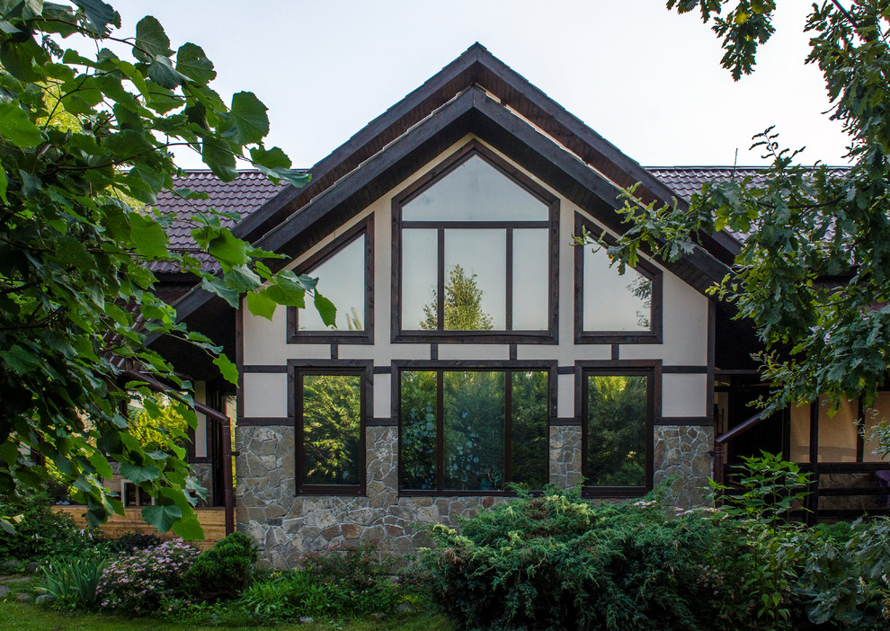 На фото: двухэтажный частный загородный дом в современном стиле с облицовкой из камня, двускатной крышей и металлической крышей с