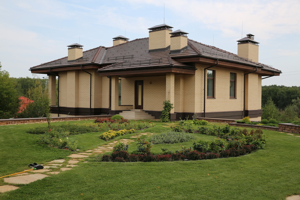 Réalisation d'une très grande façade de maison beige minimaliste en brique à deux étages et plus avec un toit à quatre pans et un toit en shingle.