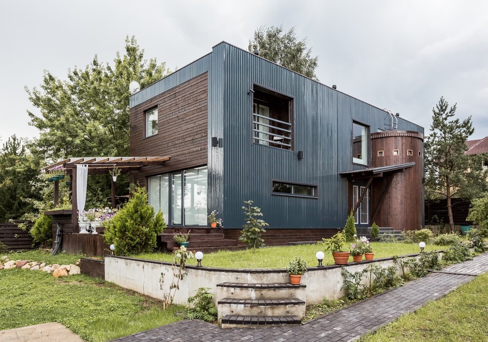 Imagen de fachada de casa industrial de dos plantas con revestimientos combinados y tejado plano