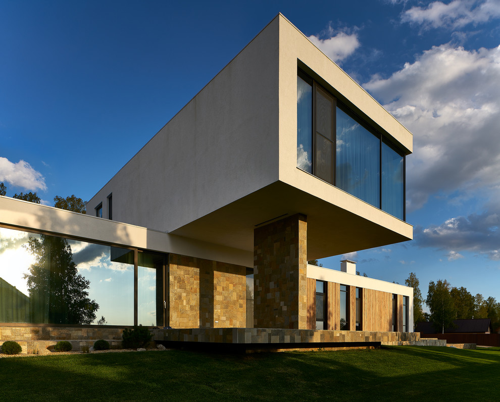 На фото: двухэтажный, бежевый частный загородный дом среднего размера в современном стиле с облицовкой из цементной штукатурки и плоской крышей с