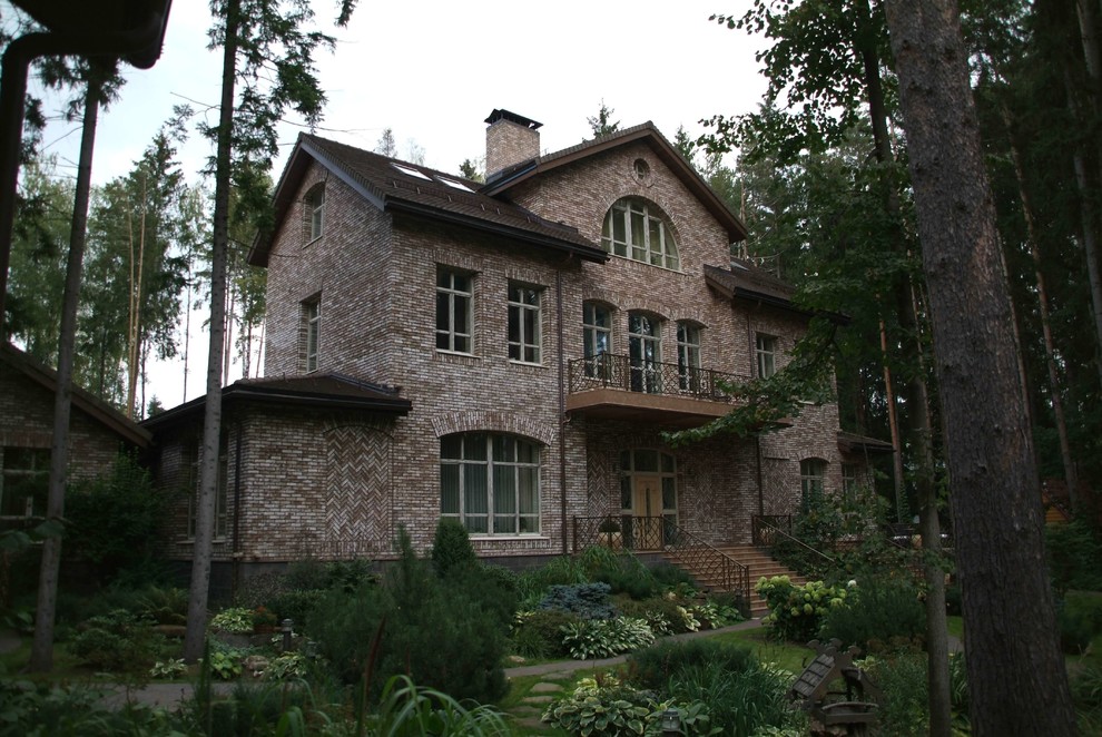 На фото: большой, трехэтажный, кирпичный, коричневый частный загородный дом в классическом стиле с двускатной крышей и черепичной крышей