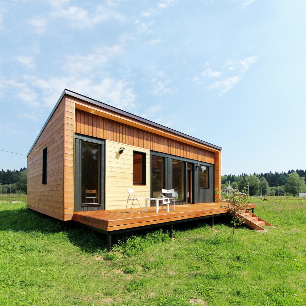 На фото: маленький, одноэтажный, деревянный, коричневый частный загородный дом в скандинавском стиле с односкатной крышей и металлической крышей для на участке и в саду с