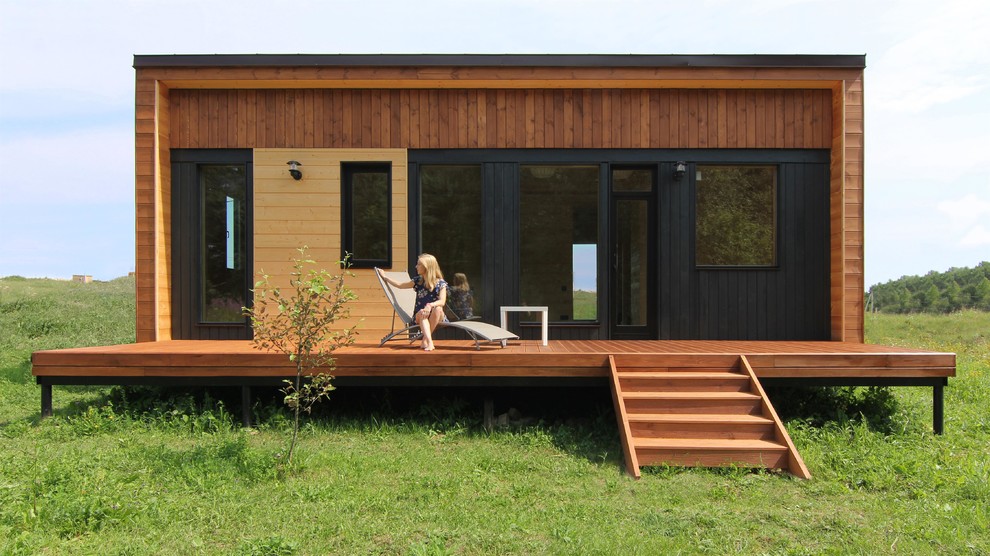 Cette photo montre une petite façade de maison marron scandinave en bois de plain-pied avec un toit en appentis et un toit en métal.