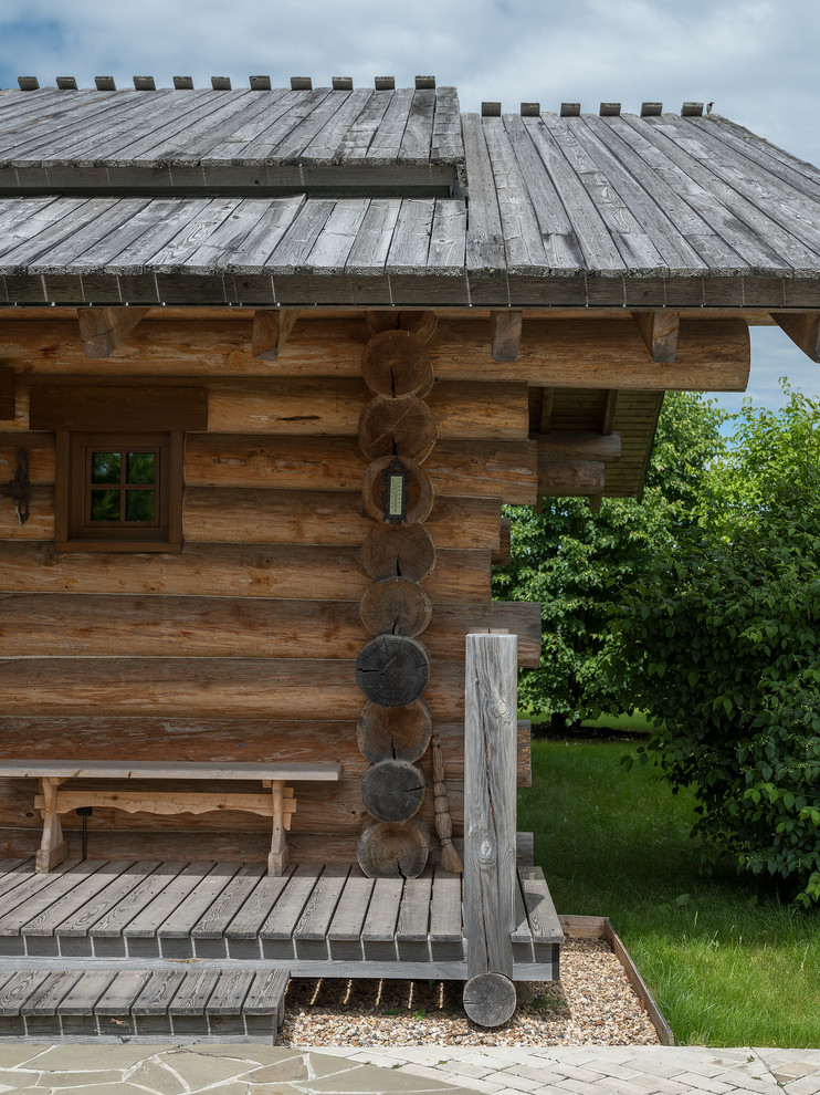 На фото: деревянный частный загородный дом в стиле рустика с двускатной крышей с