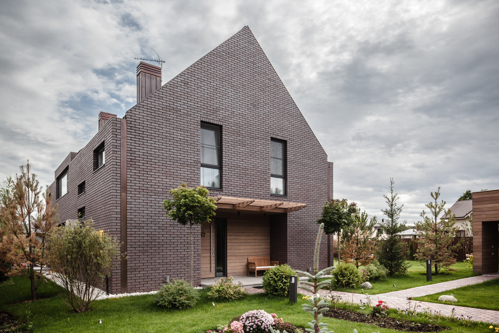 Idée de décoration pour une façade de maison marron design en brique à un étage avec un toit à deux pans.