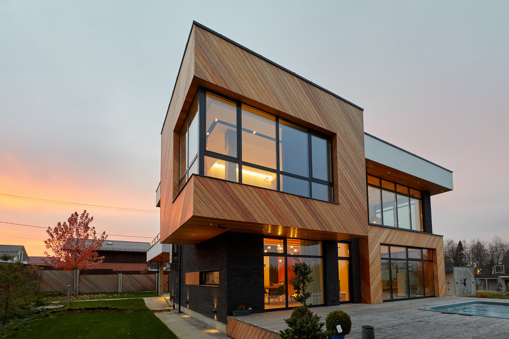 Idées déco pour une façade de maison multicolore contemporaine à un étage avec un toit plat et un revêtement mixte.