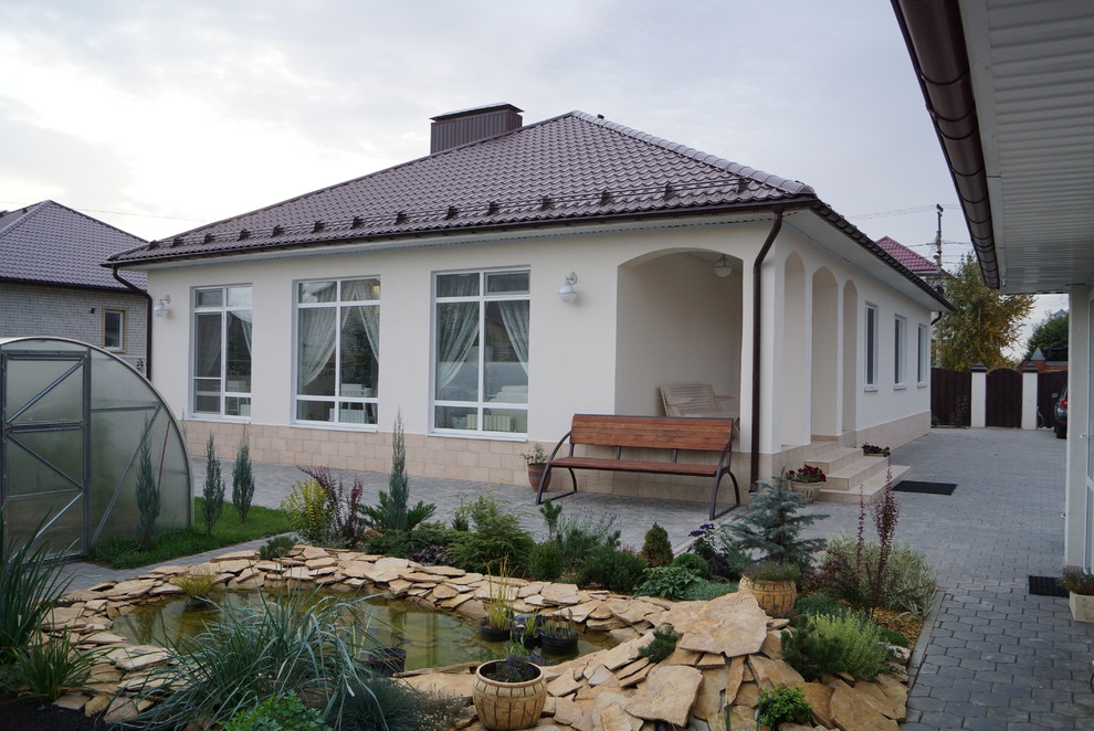 Пример оригинального дизайна: одноэтажный, бежевый дом среднего размера в современном стиле с облицовкой из цементной штукатурки и вальмовой крышей