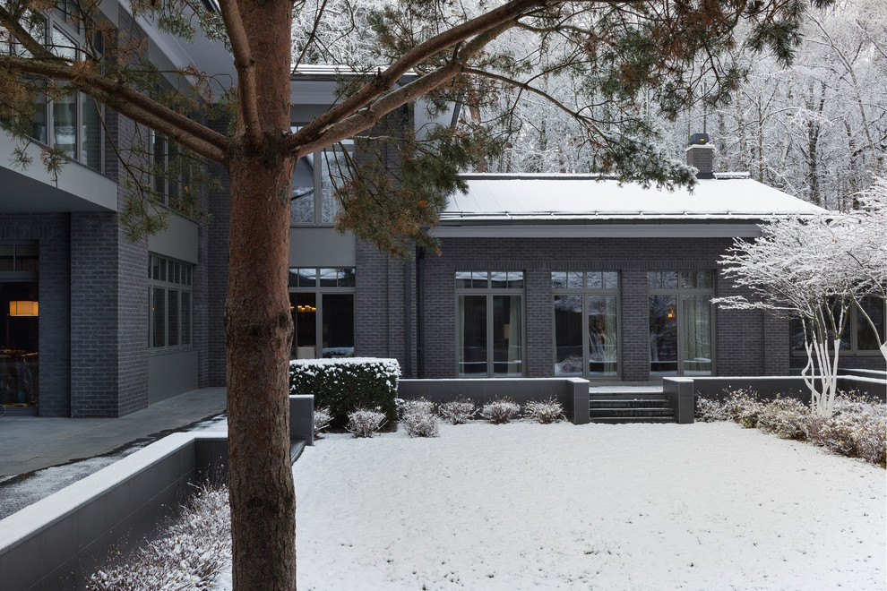 Свежая идея для дизайна: кирпичный, серый дом в современном стиле с двускатной крышей - отличное фото интерьера