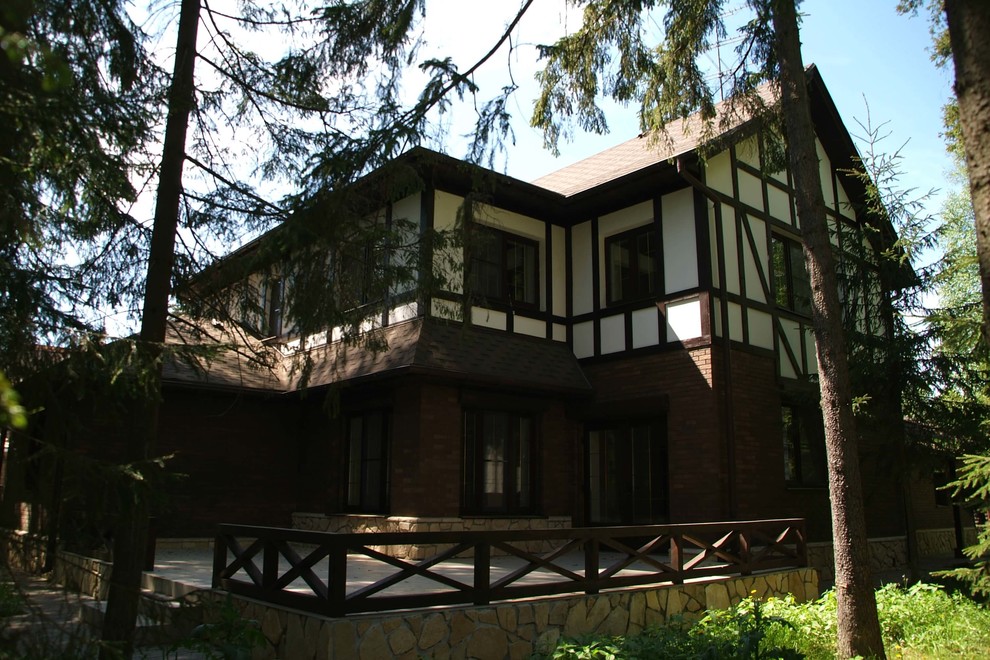 На фото: двухэтажный, разноцветный дом среднего размера в стиле кантри с комбинированной облицовкой и двускатной крышей с