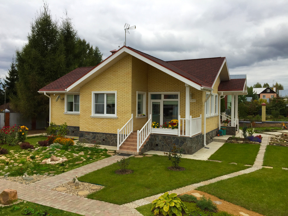 Foto della facciata di una casa piccola gialla contemporanea a un piano con rivestimento in mattoni e tetto a capanna