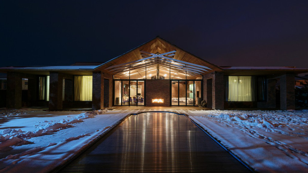 Cette image montre une grande façade de maison marron design en brique de plain-pied avec un toit à deux pans.