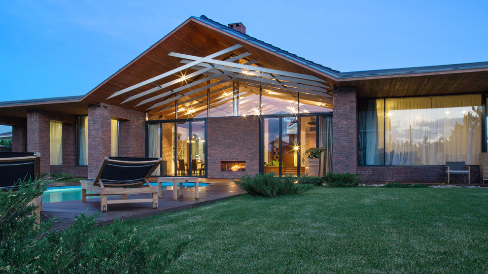 Inspiration pour une grande façade de maison marron design en brique de plain-pied avec un toit à deux pans et un toit en tuile.