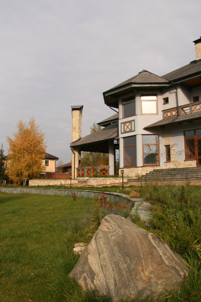 Пример оригинального дизайна: большой, трехэтажный, серый частный загородный дом в стиле кантри с облицовкой из камня и крышей из гибкой черепицы