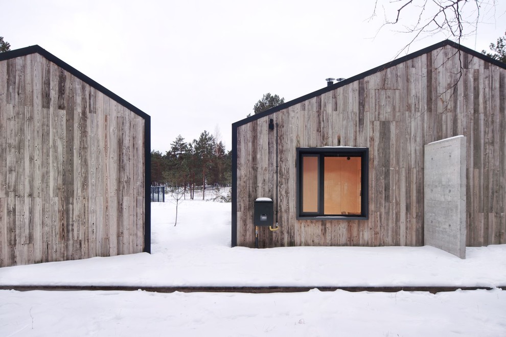 Пример оригинального дизайна: маленький, одноэтажный, деревянный, черный частный загородный дом с двускатной крышей и металлической крышей для на участке и в саду