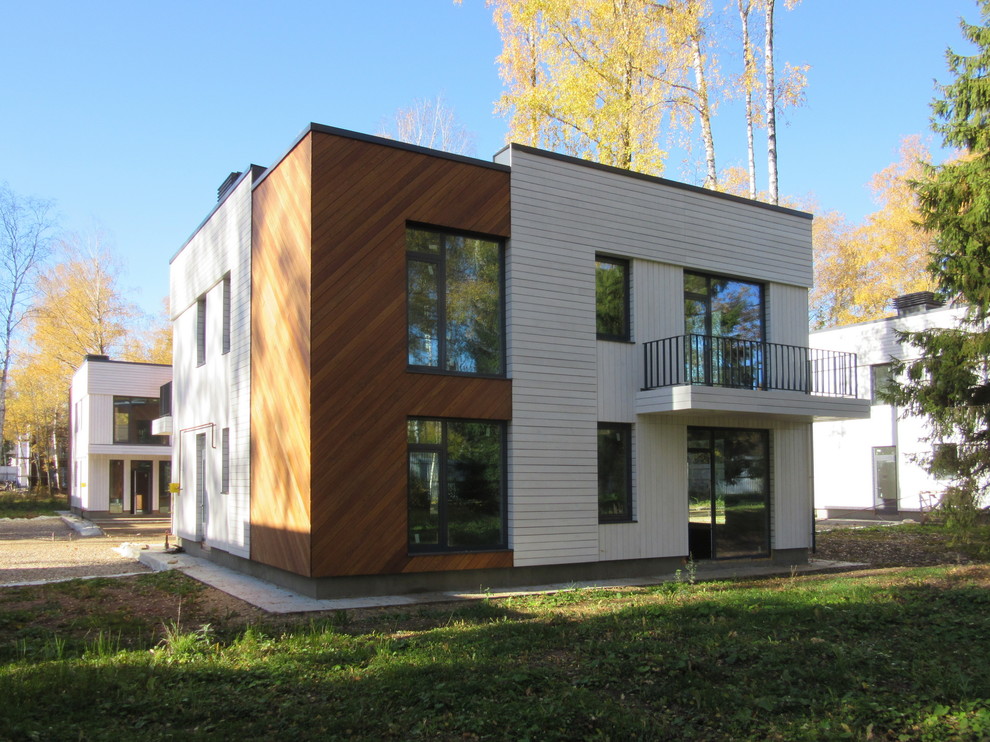 This is an example of a medium sized and multi-coloured scandinavian two floor detached house in Moscow with wood cladding, a flat roof and a mixed material roof.