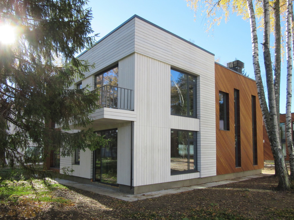 На фото: двухэтажный, деревянный, разноцветный частный загородный дом среднего размера в скандинавском стиле с плоской крышей и крышей из смешанных материалов с