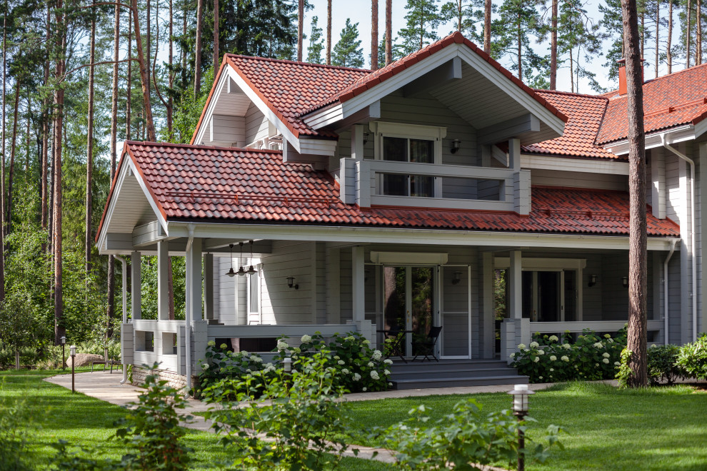 Réalisation d'une façade de maison grise design en bois à un étage avec un toit à deux pans et un toit marron.