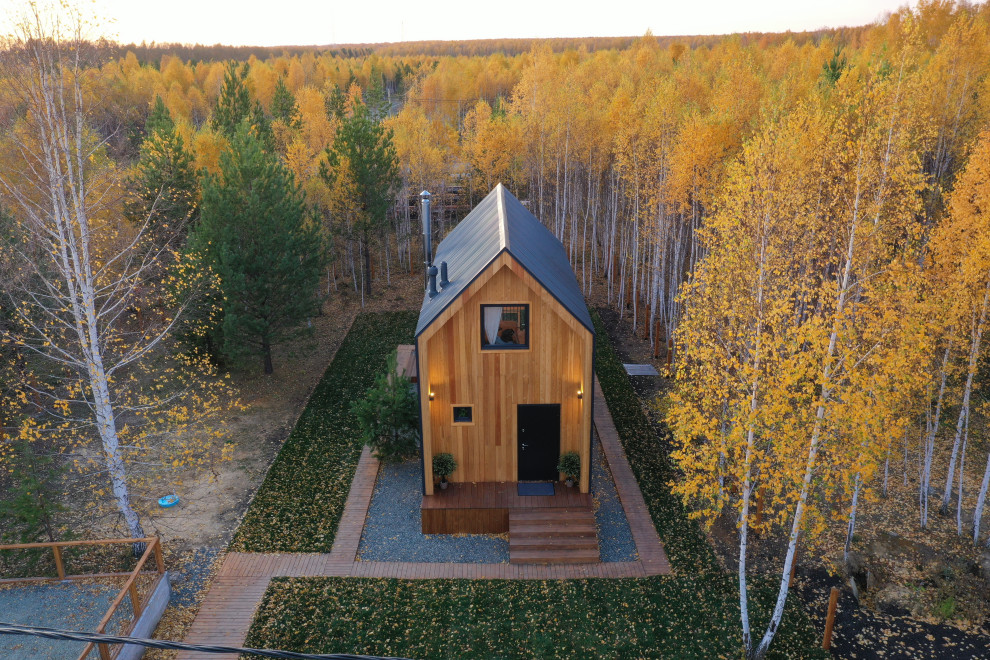 Cette photo montre une petite façade de maison marron scandinave en bois à un étage avec un toit à deux pans et un toit en métal.